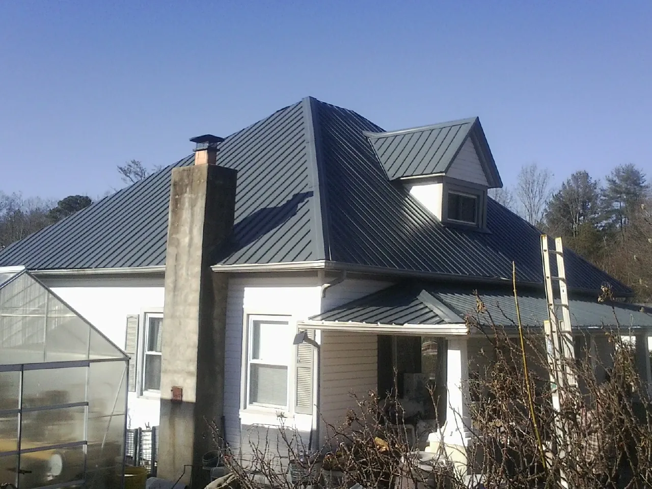 Dark blue standing seam metal roof on a white farmhouse with dormer — Slate & Tile Roof Repair by Roofing Brothers in Lagro