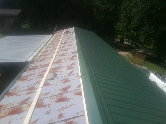 Old rusted panels beside newly installed green metal roofing — Wind Damage Roof Repair by Roofing Brothers in Lagro