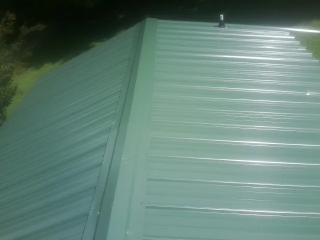 New green metal panels meeting at the ridge of a roof — Flat Roof Repair work by our crew in Lagro