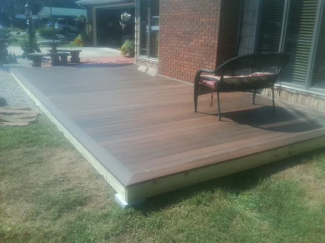 New wood deck and wicker chair beside a brick house in Lagro