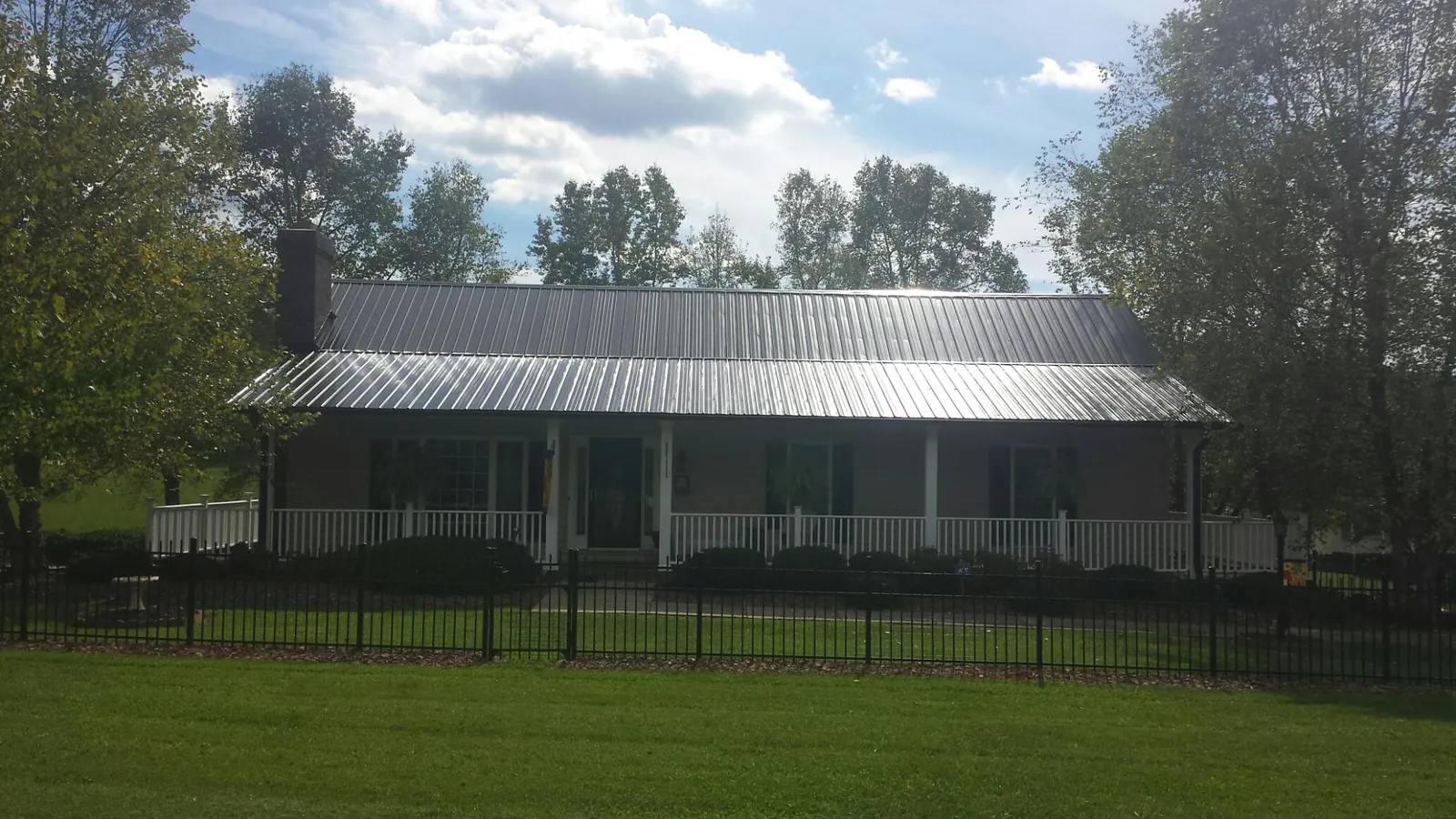 Gray metal roof on a brick ranch with a full width front porch — Gutter Guard Installation work by our crew in Lagro